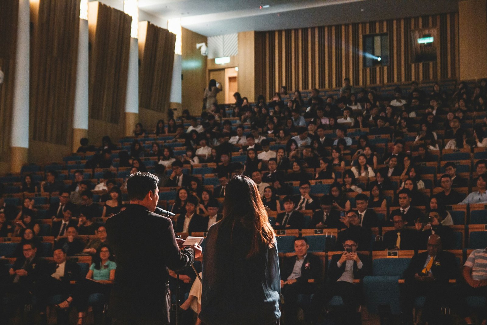 Speakers addressing a large tiered auditorium