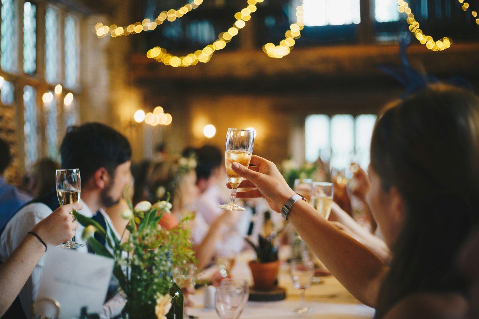 Guests toasting with champagne under string lights