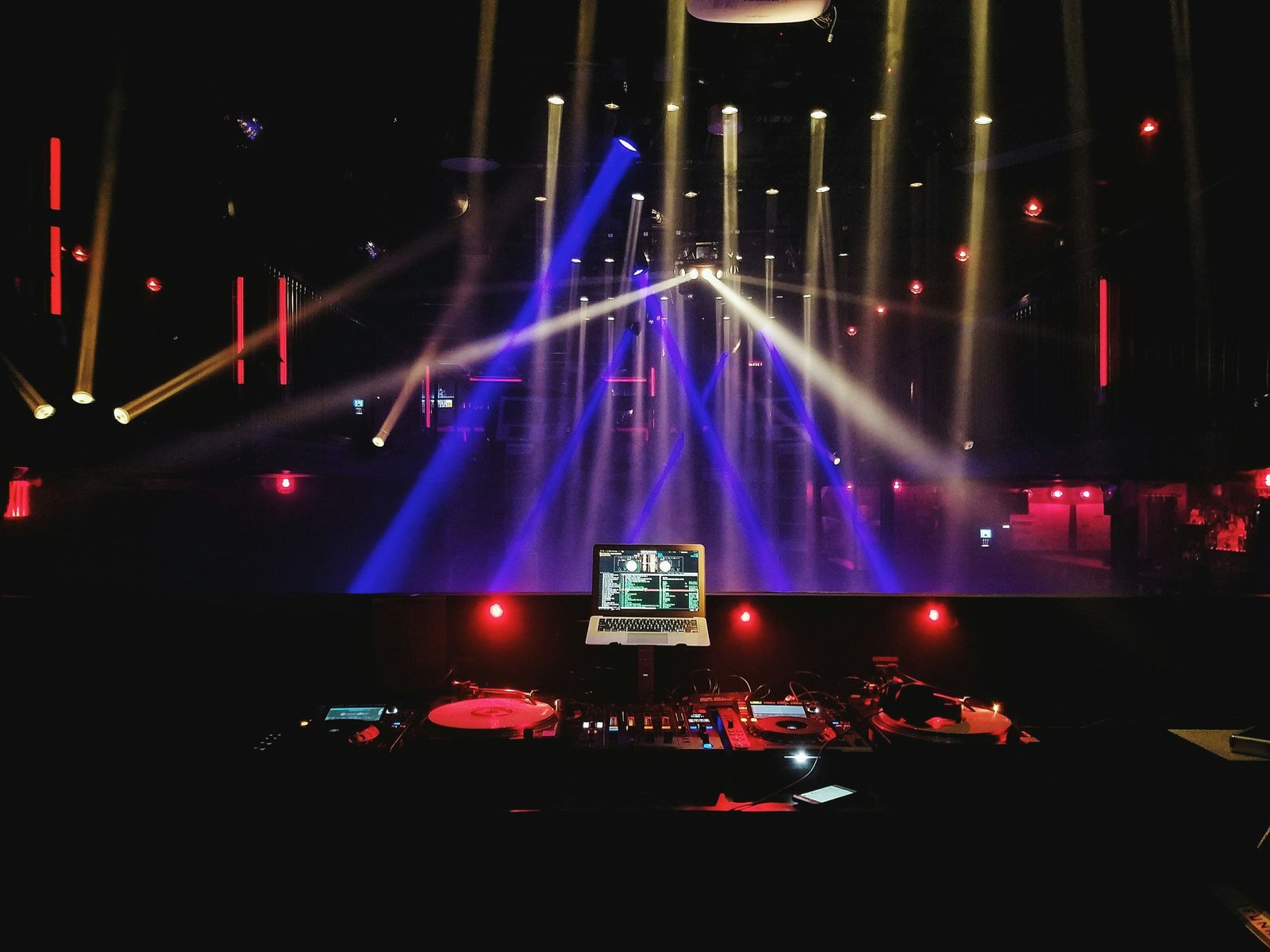A stage with beams of blue and red light above a production desk