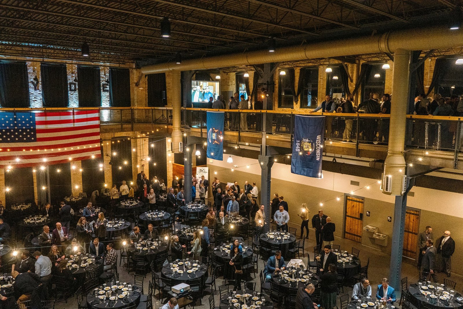A venue with round banquet tables set for guests on the floor and a mezzanine level overlooking the room